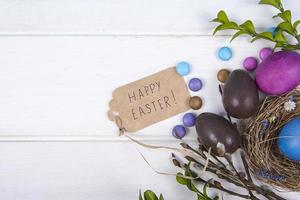 Fondo de colores con huevos de Pascua sobre fondo de tablero de madera blanca. concepto de feliz pascua. se puede utilizar como cartel, fondo, tarjeta navideña. foto