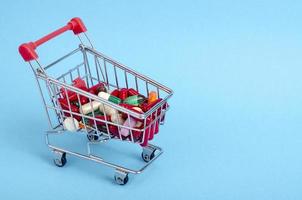 Buy medicine. Shopping basket with various medicinal, pills, tablets on blue background photo