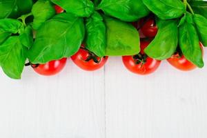 Green Fresh Basil with Tomato on White Woody Board Background photo