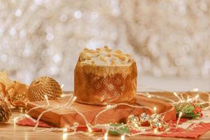 White chocolate panettone with dried apricot on wooden table with christmas ornaments photo