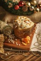 White chocolate panettone with dried apricot on wooden table with christmas ornaments photo