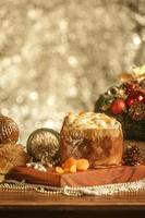 Panettone de chocolate blanco con albaricoque seco sobre mesa de madera con adornos navideños foto