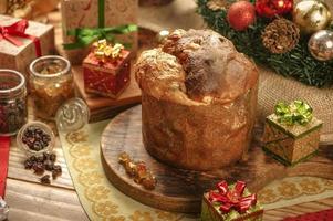 Panettone, raisins and candied fruit cubes on wooden cutting board with christmas ornaments photo