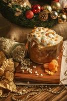 Panettone de chocolate blanco con albaricoque seco sobre mesa de madera con adornos navideños foto