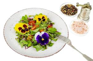 Vegetable salad with edible flowers on white background. photo