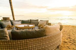 Almohadas en la tumbona del patio al aire libre en la playa con la hora del atardecer