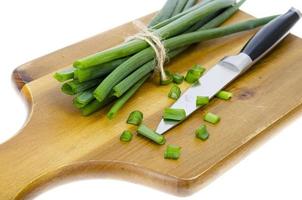 Wooden kitchen cutting board for slicing fresh green onions. photo