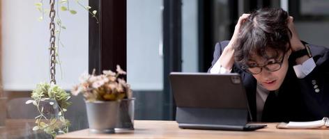 Young businessman or manager upset by bad news received by email sits at a table, uses laptop photo