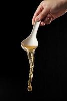 Spoon pouring noodle soup isolated on black background photo