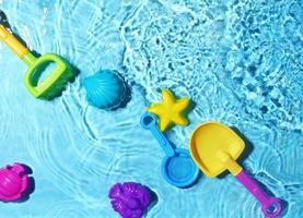 juguetes de playa para niños sobre salpicaduras de agua. foto