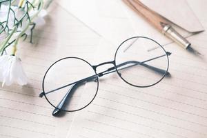 notepad, eyeglass and a pencil on wooden table photo