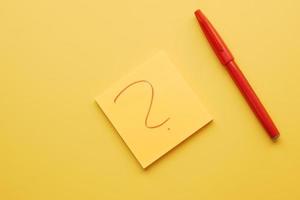 high angle view of question mark on paper on yellow background photo