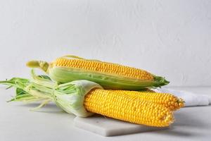 Junta con mazorcas de maíz frescas sobre fondo claro