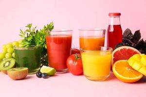 Glasses with healthy juice, fruits and vegetables on color background