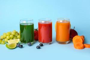 Glasses with healthy juice, fruits and vegetables on color background photo