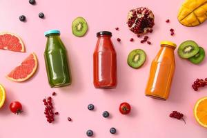 Bottles with healthy juice, fruits and vegetables on color background photo