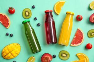 Bottles with healthy juice, fruits and vegetables on color background photo