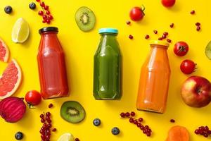Botellas con jugos saludables, frutas y verduras sobre fondo de color foto