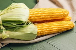 Mazorcas de maíz fresco sobre fondo de madera de color foto