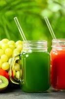 Mason jars with healthy juice, fruits and vegetables on table outdoors, closeup photo