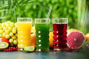 Glasses with healthy juice and fruits on table outdoors, closeup