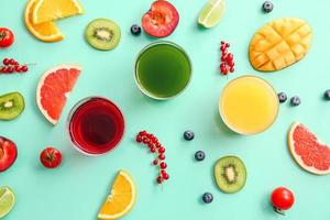 Glasses with healthy juice, fruits and vegetables on color background photo