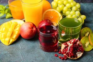 Vasos con jugos saludables, frutas y verduras sobre fondo oscuro foto