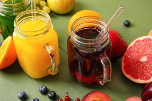 Frascos de albañil con jugos saludables, frutas y verduras sobre fondo de madera de color