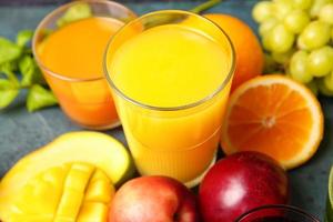 Vaso con jugos saludables, frutas y verduras sobre fondo oscuro foto