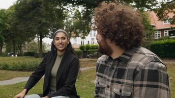 Woman and man talking whilst sitting in park video