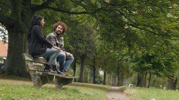Mujer y hombre hablando mientras está sentado en un banco en el parque video