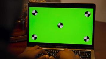 homem digitando no laptop com tela verde