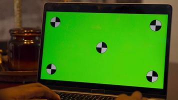 homem de mãos dadas acima das teclas do laptop com tela verde video
