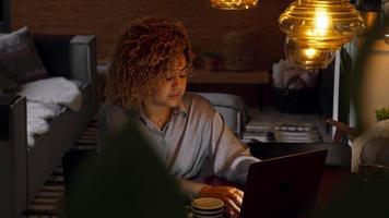 mujer sentada en la mesa y escribiendo en la computadora portátil
