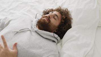 uomo sdraiato sulla schiena che ascolta musica con gli occhi chiusi