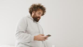 Man plops down on bed and watches smartphone lying on his back video