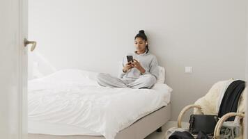 mujer sentada en la cama con pantalla táctil smartphone video