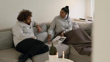 Woman and man on sofa looking in magazine video