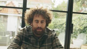 Man at table with smartphone looking up seriously into camera lens video