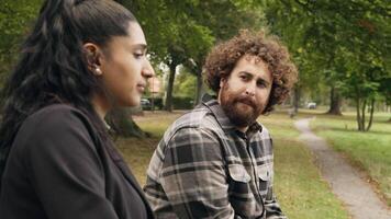 Woman and man talking whilst sitting in park video