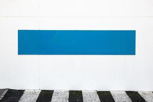 Blank blue sign placed on white wall on the outside of building. Template mock up photo