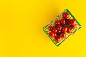 Cherry tomatoes in a basket on a bright yellow background with an empty place for an inscription. photo