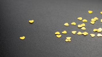 Gold glitter hearts on a black background close-up. photo