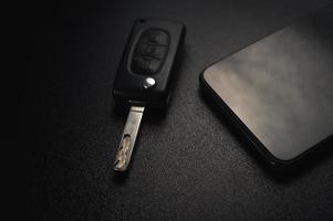 Car keychain and smartphone lie on a black panel photo
