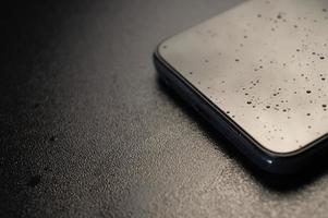 Black smartphone in splashes of liquid on a black background photo