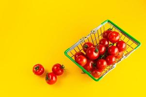 Cherry tomatoes in a basket on a bright yellow background with an empty place for an inscription. photo