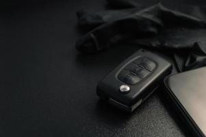 Car key with black gloves and a smartphone lie on a black table photo