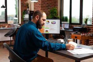 Hombre empresario sentado en la mesa de escritorio analizando documentos comerciales trabajando en una presentación de marketing