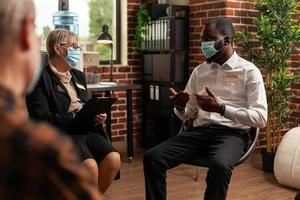 African american man having discussion at aa meeting with people sitting in circle photo