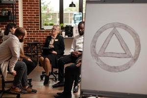 Patients sitting in circle at group therapy program while having aa meeting symbol photo